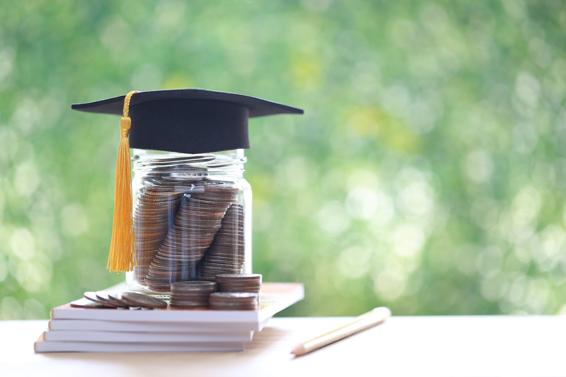 Coin jar with graduation cap sitting on notebooks